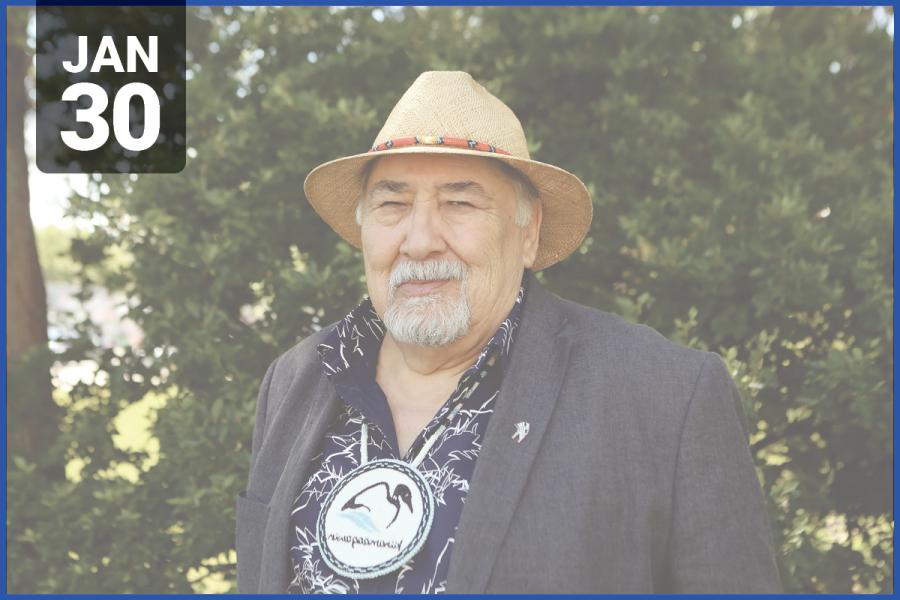 Headshot of Elder Valdie Seymour standing in front of green foliage wearing a woven hat and blazer.